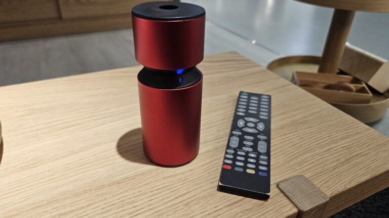 鋁合金圓柱造型的擴香儀，放在木質茶几上。