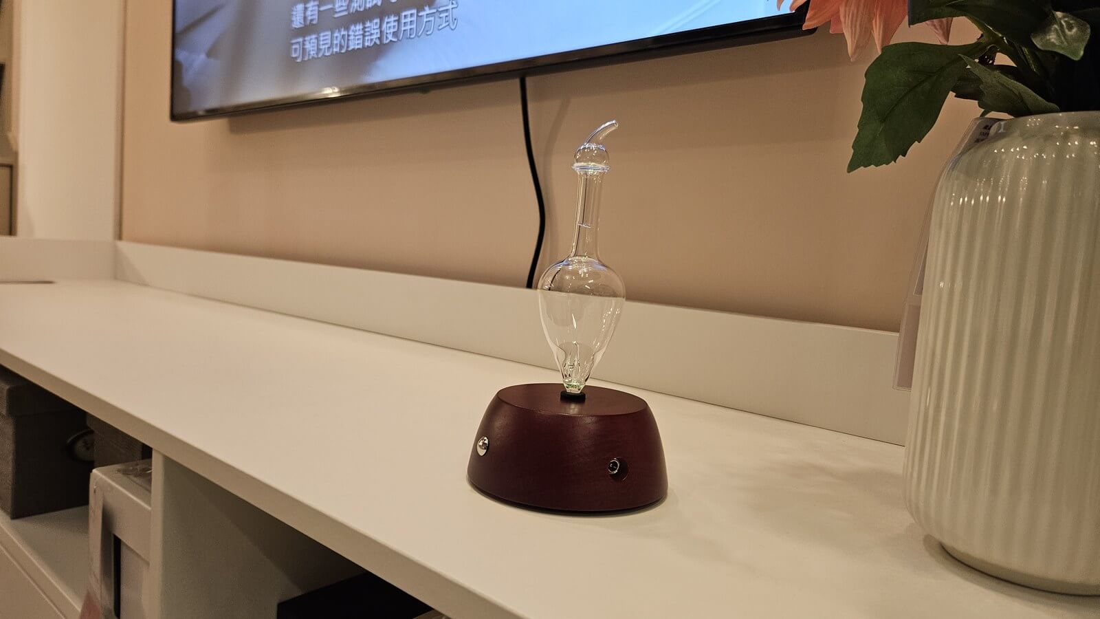 深木色底座搭配玻璃導管的擴香儀，擺在客廳電視櫃上