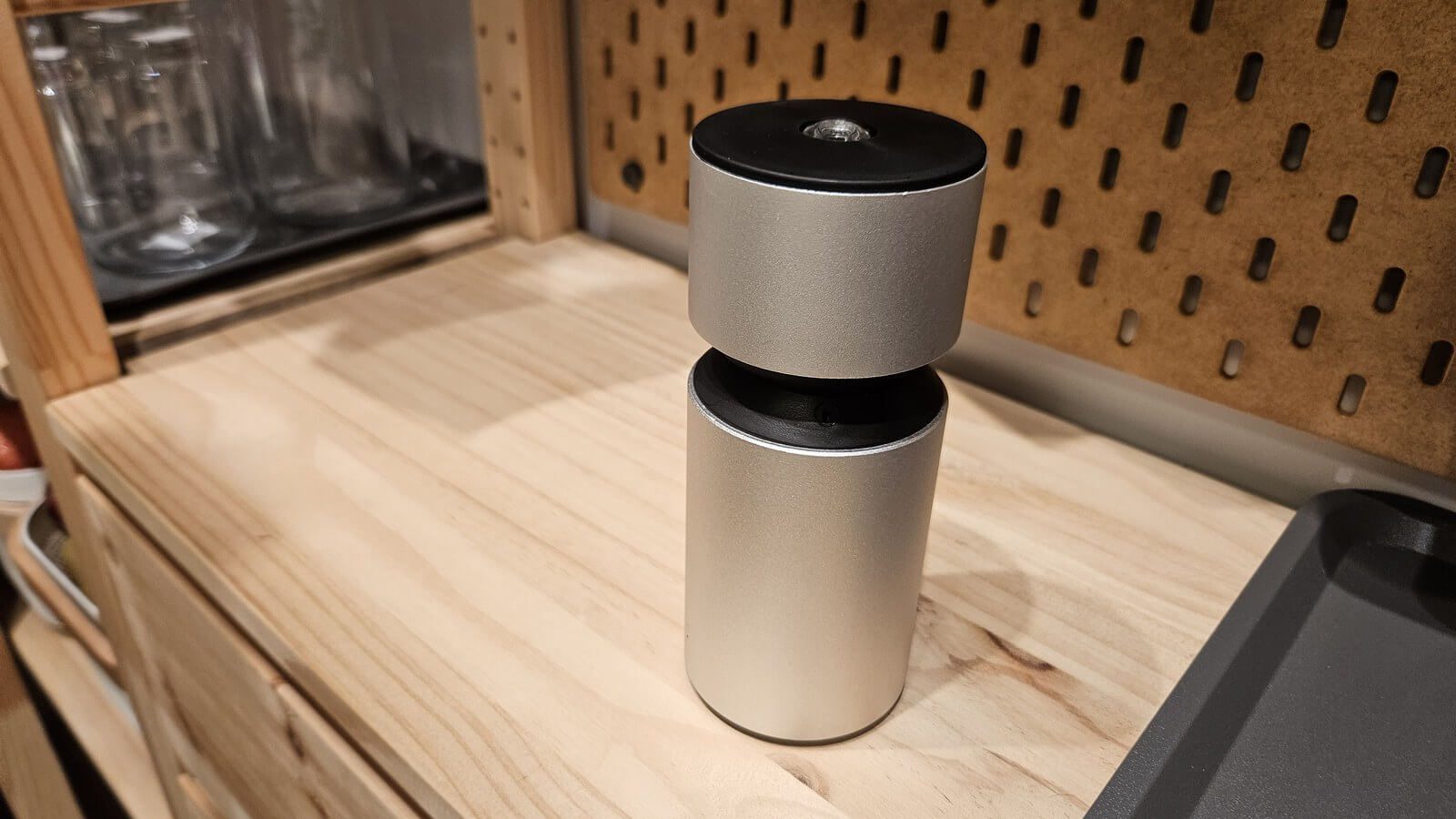 銀色鋁合金圓柱機型的無水精油擴香機，放在木質檯面前