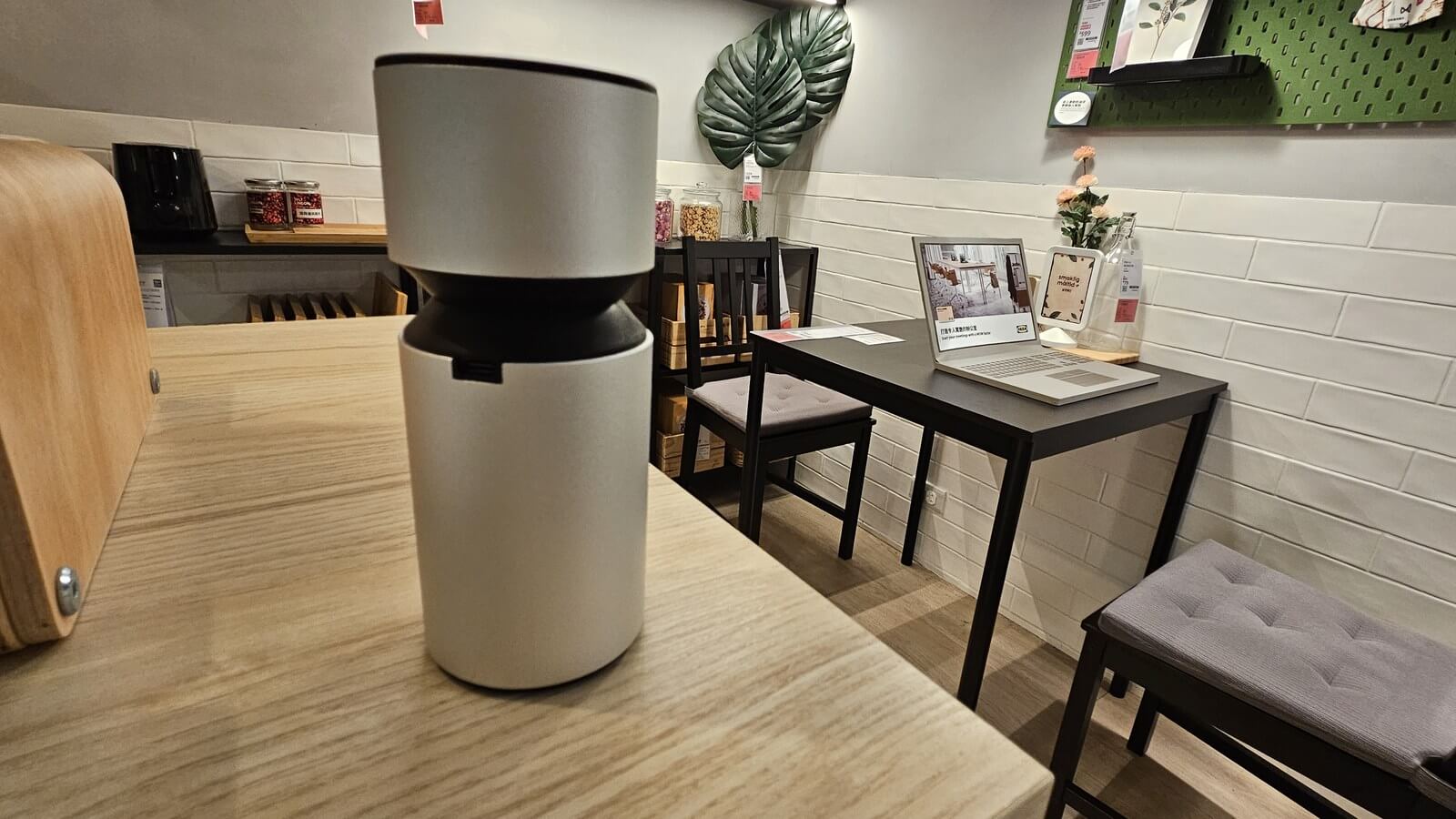 鋁合金圓柱造型擴香儀放在木桌上，店面空間情境