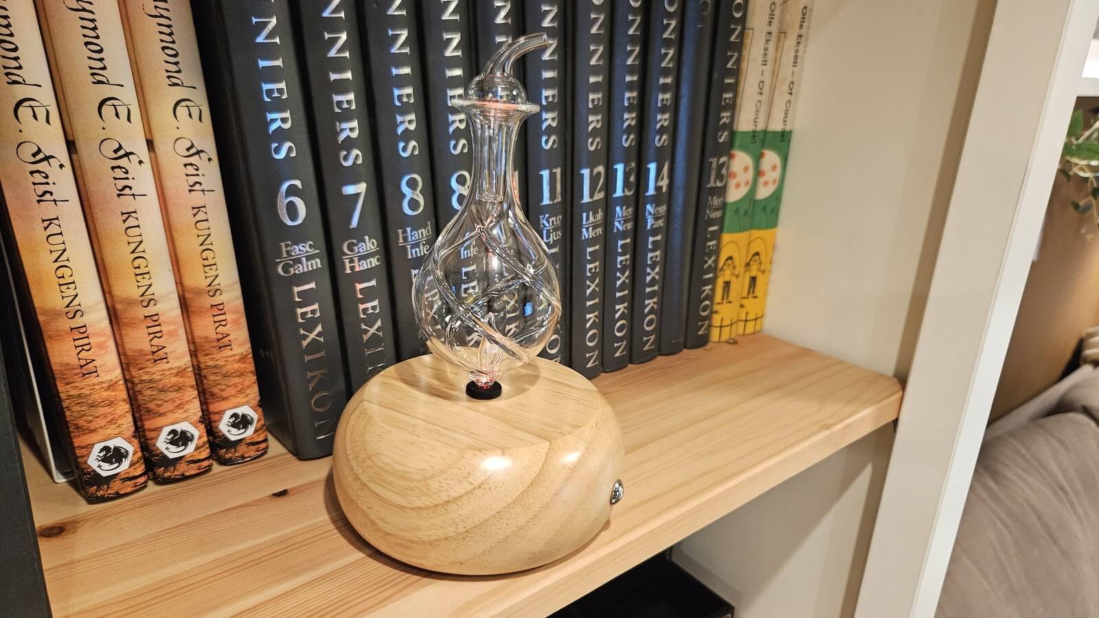 淺木色旋紋木座擴香儀擺在書架上，玻璃瓶身造型