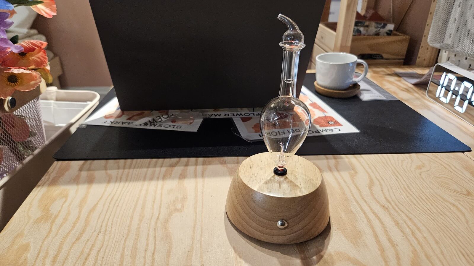 木質底座擴香儀放在木桌上，旁邊有馬克杯與時鐘